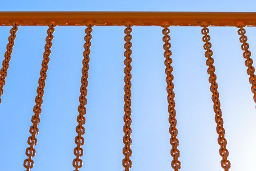 yellow railing with chains on blue sku background with selective focus