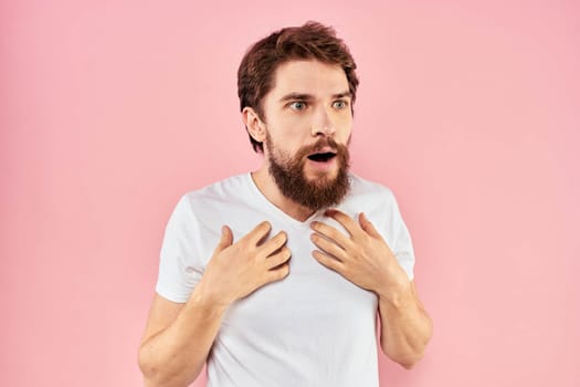 Man in white t-shirt gestures with hands emotions lifestyle cropped view pink background. High quality photo