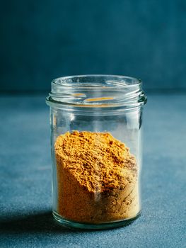 Indian or pakistani masala powder in glass jar. Homemade dry curry garam masala mix spices blend on dark gray background. Vertical