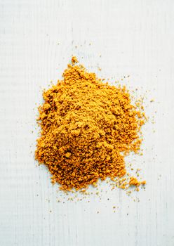 Heap of garam masala spice on white wooden background. Indian or pakistani masala powder heap, top view or flat lay