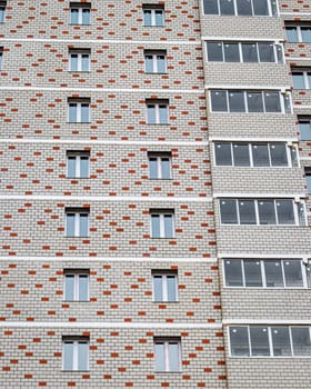 Fragment of a white brick residential building with balconies.