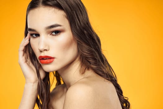 beautiful brunette red lips bare shoulders skin care yellow background. High quality photo