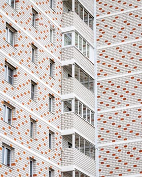 Fragment of a white brick residential building with balconies.