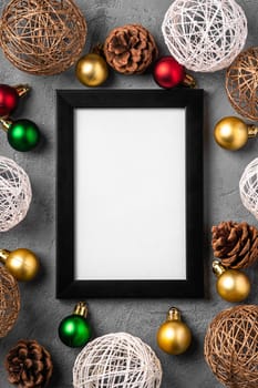 Christmas composition with empty picture frame. Colorful baubles and pine cones decorations. Mockup greetings card template