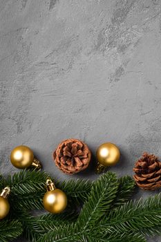 Christmas composition. Golden baubles, pine cones and fir needles decorations on grey background. Top view copy space
