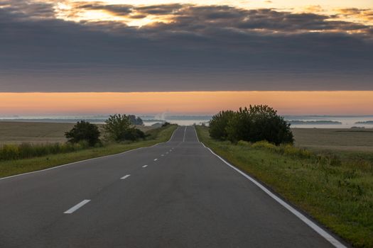 Open straight road at foggy morning flatland with muted colors