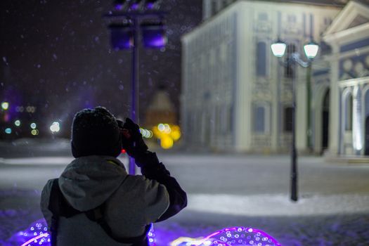 professional photographer shooting night architecture view handheld at snowy winter with natural light and selective focus
