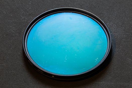 old rotary polarizing filter with scratches on dark background.
