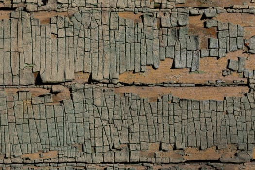 Closeup shot of peeling faded green paint on horizontal wooden planks under direct sunlight