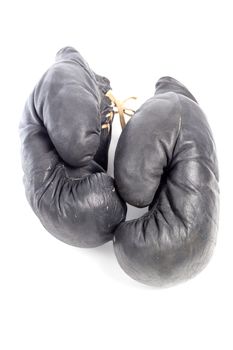 Old black leather boxing gloves isolated on white background with shadows lying on flat surface. Horsehair stuffed.