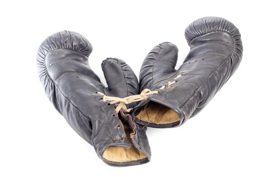Old black leather boxing gloves isolated on white background with shadows lying on flat surface. Horsehair stuffed.