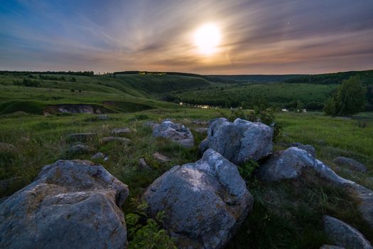 night glacial stones in field landscape under moonlight halo