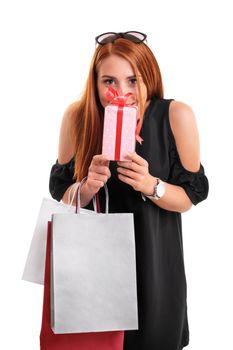 Beautiful young woman in a black dress holding shopping bags and present, isolated on a white background. Shopping concept. Gift concept.