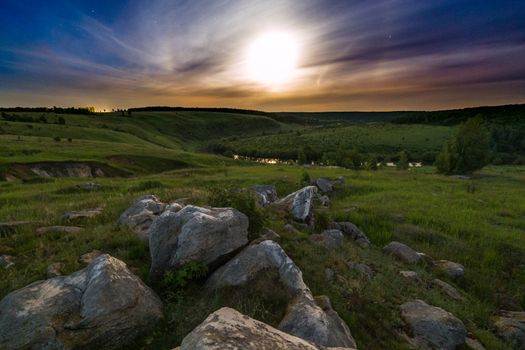night glacial stones in field landscape under moonlight halo