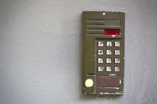 Old digital doorphone with silver buttons on gray oil painted flat surface