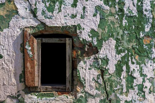 old wall with peeling green paint, white plaster and small empty ticket window