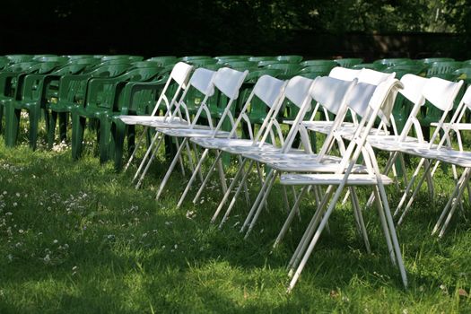 Green and white plastic outdoor chairs for an audience