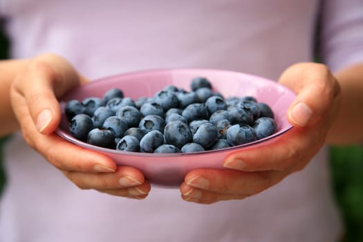 Hands holding a bowl with blueberries