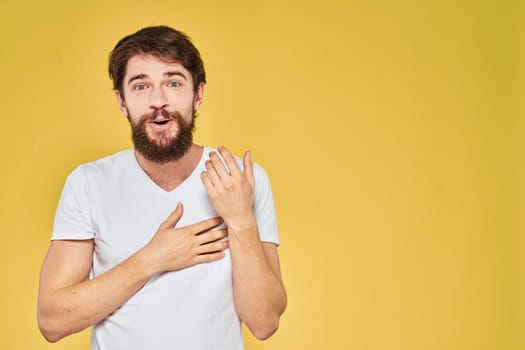 Bearded man white t-shirt emotions gestures with hands fun yellow background. High quality photo