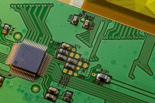 Classic small green electronic PCB circuit LCD control background, close up microchip and components with part of flexible cable.