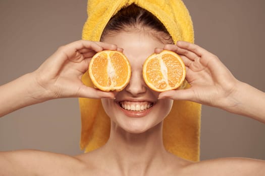 woman in a yellow towel on her head oranges close-up beige background. High quality photo