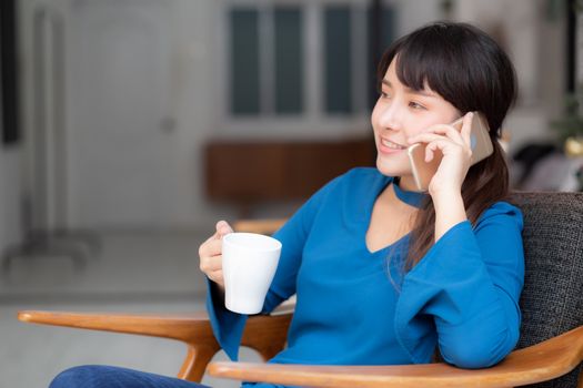 Beautiful portrait young asian woman smiling using mobile smart phone talking enjoy and drink coffee with relax, girl sitting on chair, communication concept.