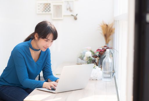 Beautiful portrait asia young woman working online on laptop sitting at cafe shop, professional female freelance using notebook computer, business and communication concept.