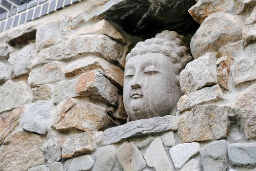 Closeup of Teh Buddha Head stone statue at entrance gate in Haedong Yonggungsa Temple at Busan, South Korea.