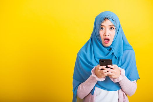 Asian Muslim Arab, Portrait of happy beautiful young woman Islam religious wear veil hijab funny smile she reads surprised confused shock news open mouth, studio shot isolated on yellow background