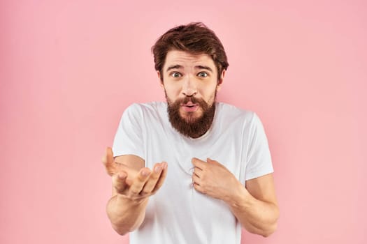 Man in white t-shirt gestures with hands emotions lifestyle cropped view pink background. High quality photo