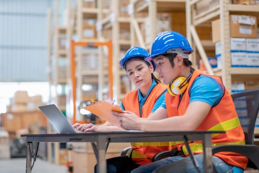 Warehouse man and woman or factory workers sit on chairs and discuss together about stock of products in workplace area. Concept of good management and happiness of staff work industrial business.