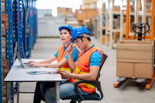 Warehouse man and woman or factory workers sit on chairs and discuss together about stock of products in workplace area. Concept of good management and happiness of staff work industrial business.