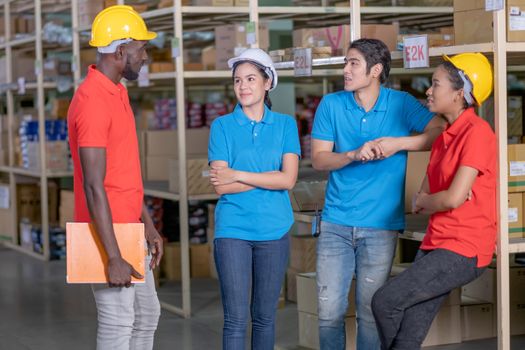 Group of warehouse or factory workers stay and talk together during breaking from work and they look relax in workplace area. Concept of support system for staff in delivery industrial business.