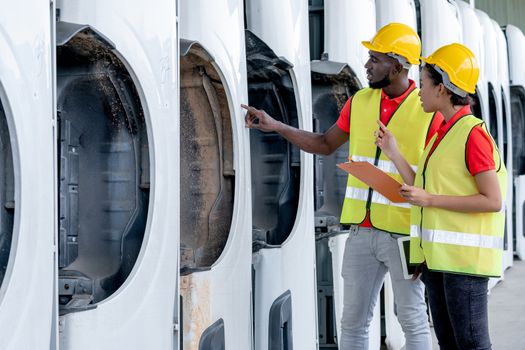 African American warehouse man and woman or factory worker work and discuss together about vehicle parts in workplace area. Concept of good management of staff working.