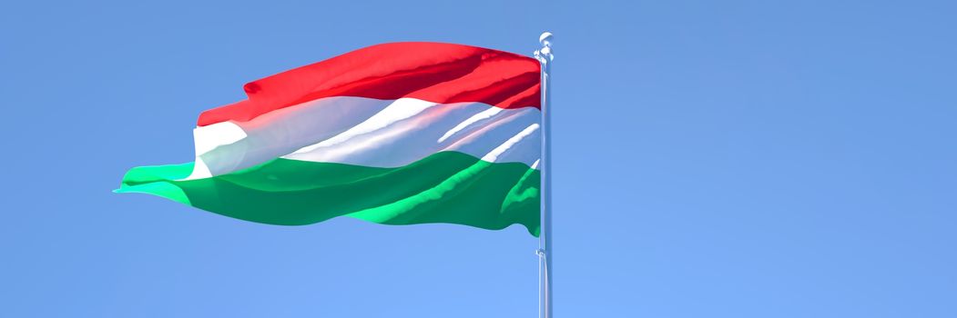 3D rendering of the national flag of Hungary waving in the wind against a blue sky.