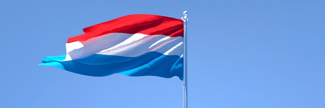 3D rendering of the national flag of Netherlands waving in the wind against a blue sky