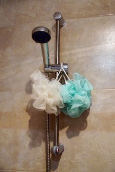 two sponges for body hang on the shower rack in the bathroom.