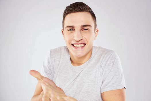 Man in a white t-shirt emotions gestures with hands close-up cropped view light background. High quality photo