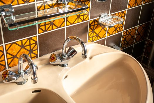 Retro and vintage bathroom sink, with mid century tiles, orange and brown colored.