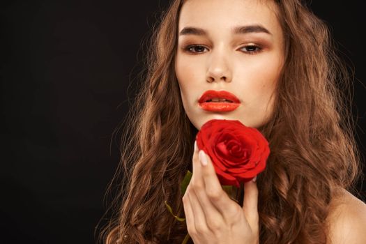 woman with a red rose on a dark background long hair makeup red lips. High quality photo