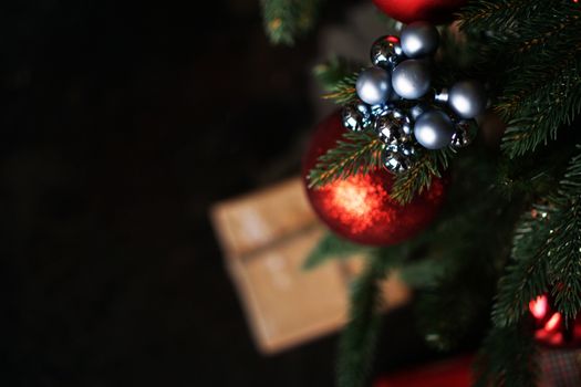 Shiny Christmas red ball hanging on pine branches with festive dark background