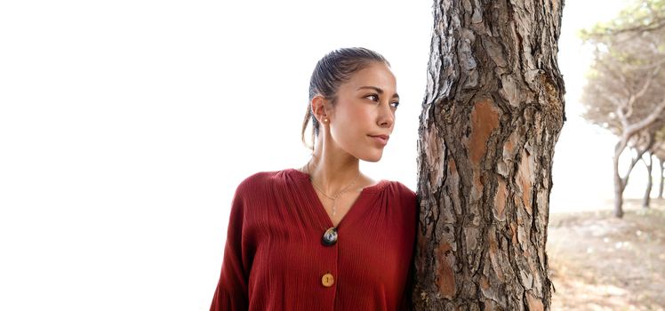 Half-length portrait of a beautiful young Caucasian woman with her hair gathered up that highlights the perfect features of the face - Close up of model posing near a tree with large white copy space