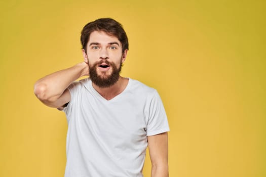 Man gesturing with hands emotions lifestyle white t-shirt yellow isolated background. High quality photo