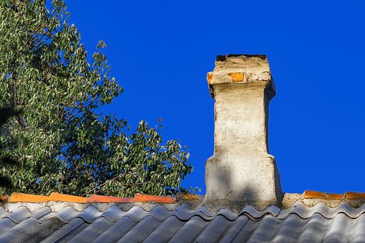 Smoke pipe and roof of old house Last century against the blue sky. Front view.