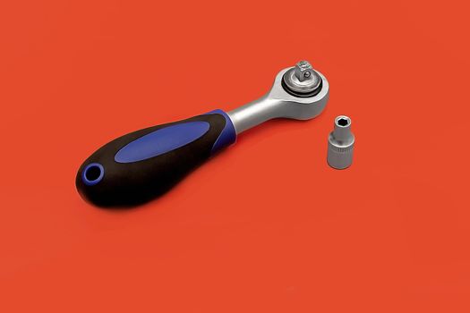 Tools for work, semi-automatic screwdriver with black plastic handle on red background.