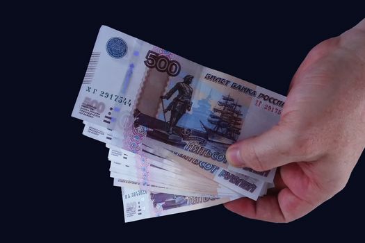 In the hand of the banknotes on dark background