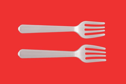 Two plastic white forks on a red background