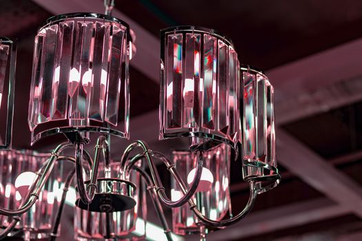 Fragment of a pink glass chandelier against the ceiling.
