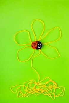 One eraser shaped like a ladybird on a stylised flower made with yellow thread , the background is green , fantasy has no limit