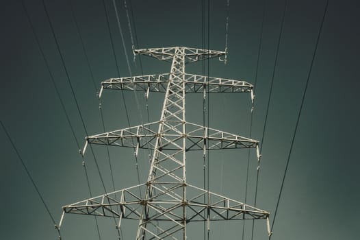 The support of the high voltage line in winter. View from below. Gradient sky. Vertical image.
